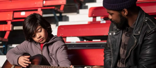 Joe and Larry practice guitar at Yankee stadium.