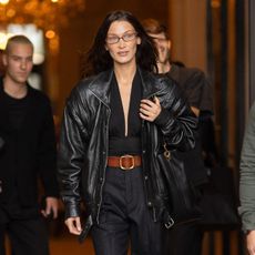 Bella Hadid wears a Saint Laurent leather jacket, black top and pinstripe trousers. 
