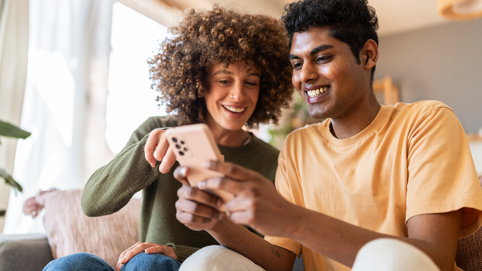 two people looking at smartphone together on the sofa