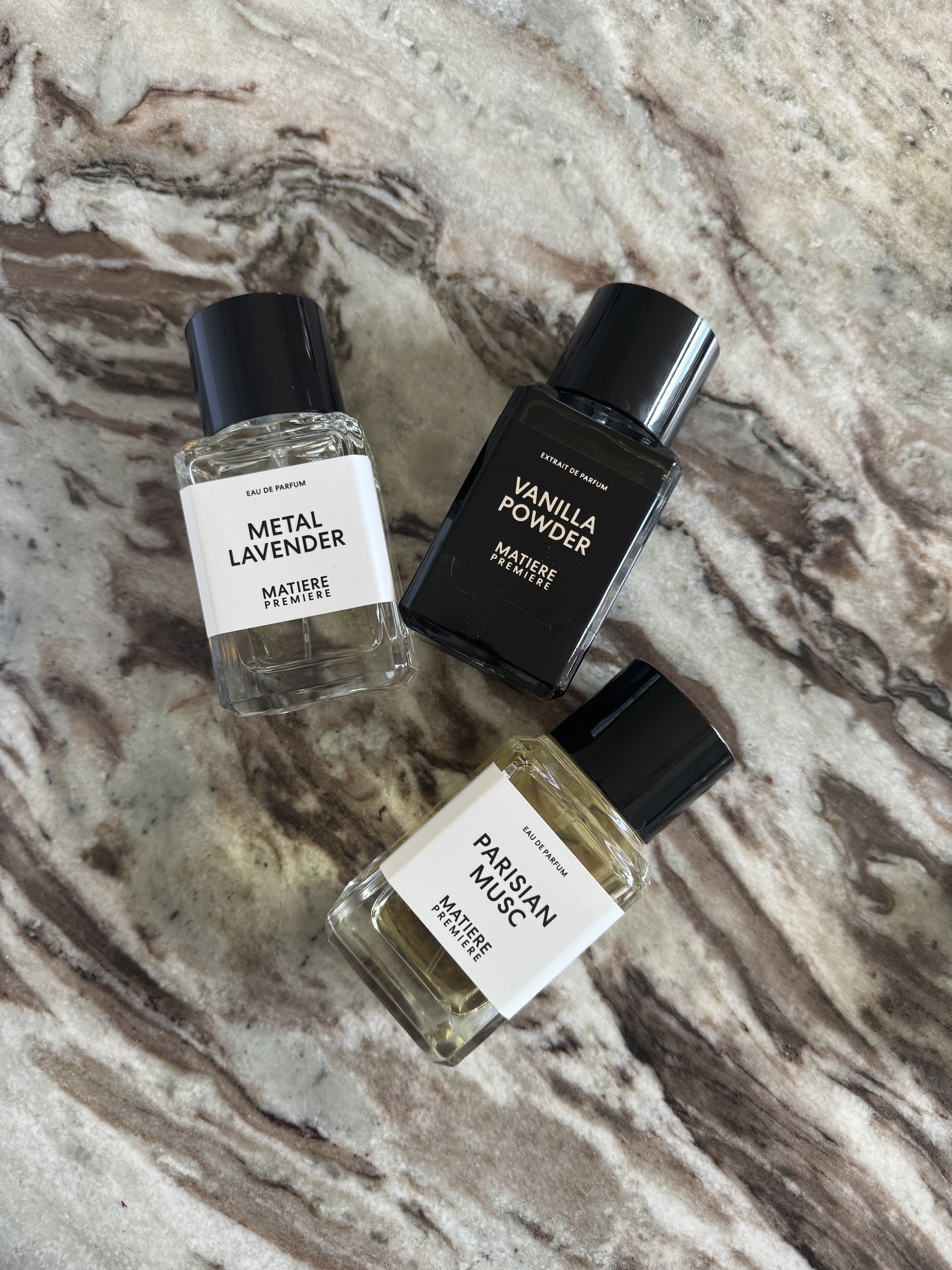 Matiere Premiere perfume bottles on a marble table, including Metal Lavender, Vanilla Powder and Parisian Musc