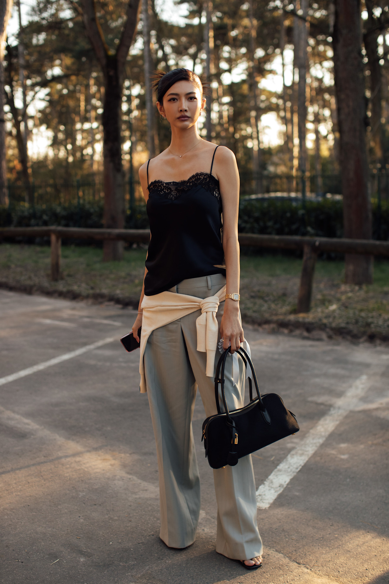 woman wearing a lacy black cami, gray trousers, and a white sweter in paris