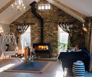 Modern living room with blue rug in front of black fireplace and thin chimnent flue