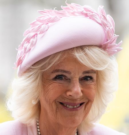 Queen Camilla wearing a pink hat and coat and smiling at the camera on Commonwealth Day 2025