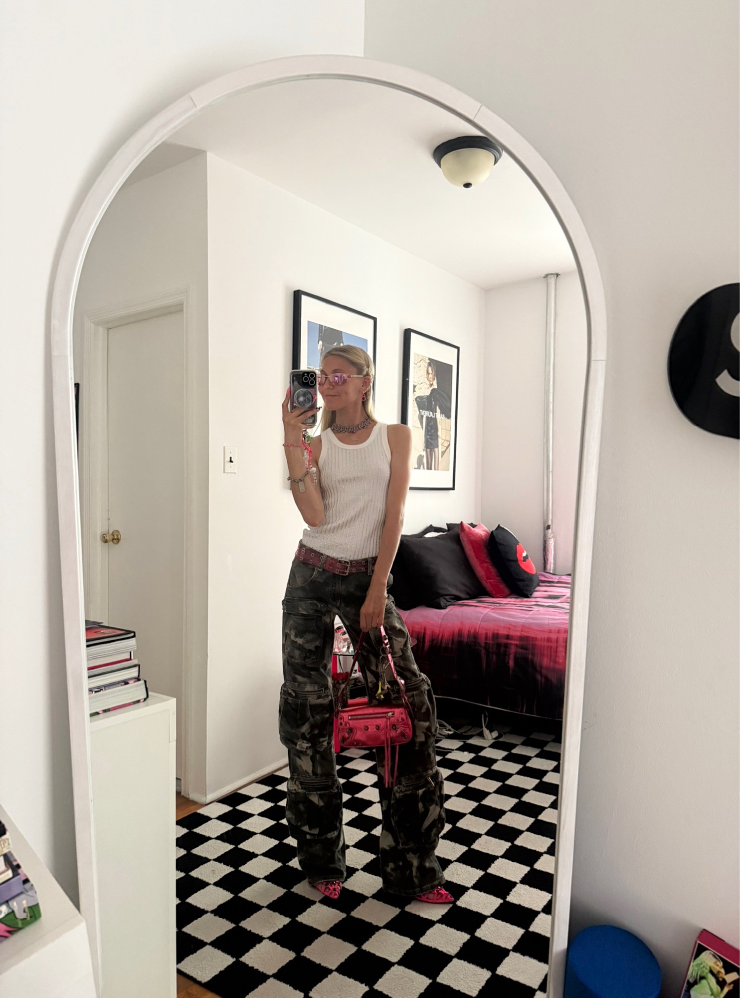 Jessica Minkoff posing in mirror wearing white tank top and camo pants