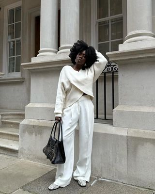 @daniellejinadu wearing white trousers, jumper and snakeskin loafers