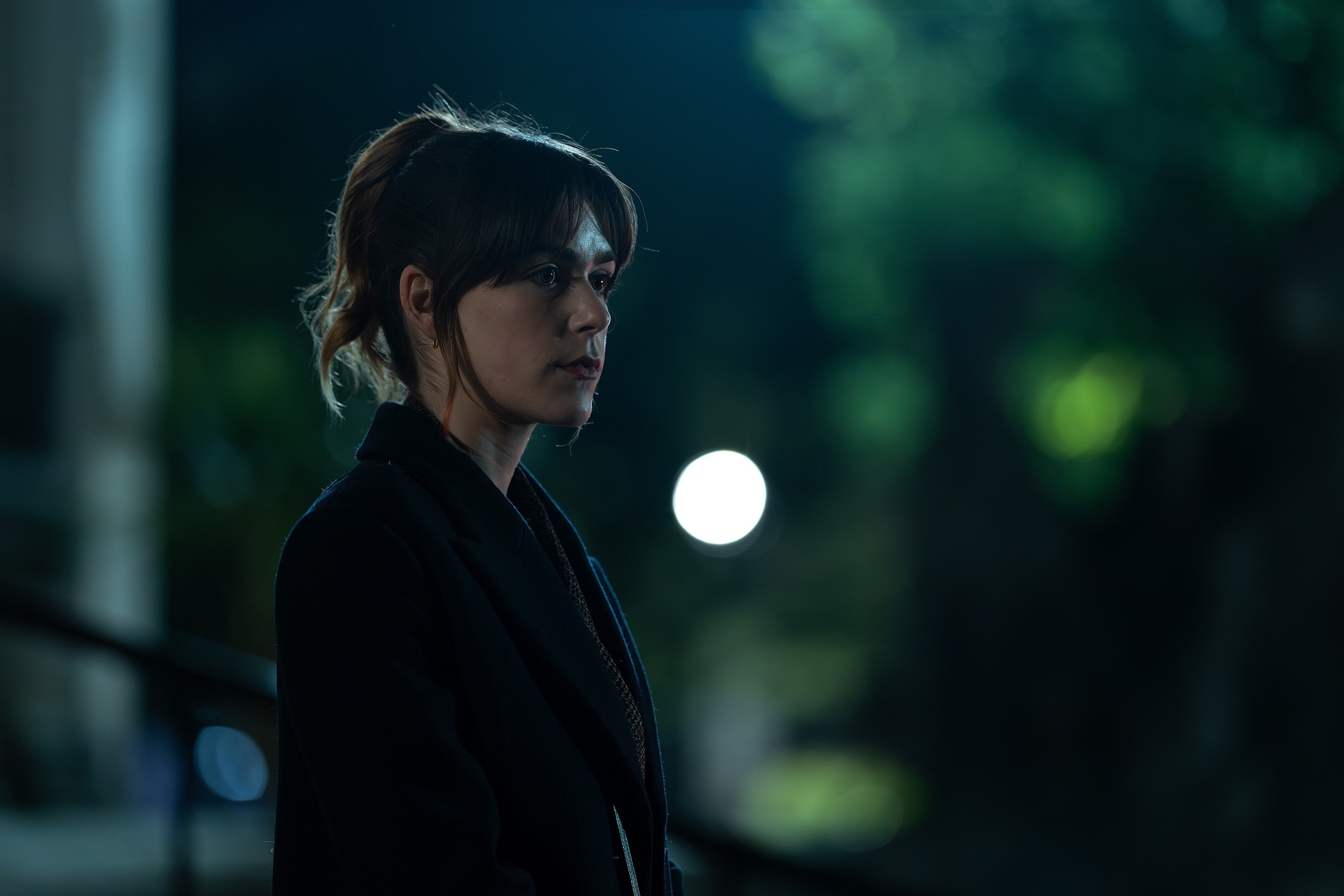 kiernan shipka as haley standing on a dark london street in a peacoat with her hair in a pony tail in season 4 of industry
