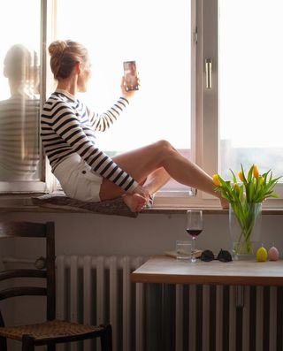 Woman Sitting on Windowsill on Video Call