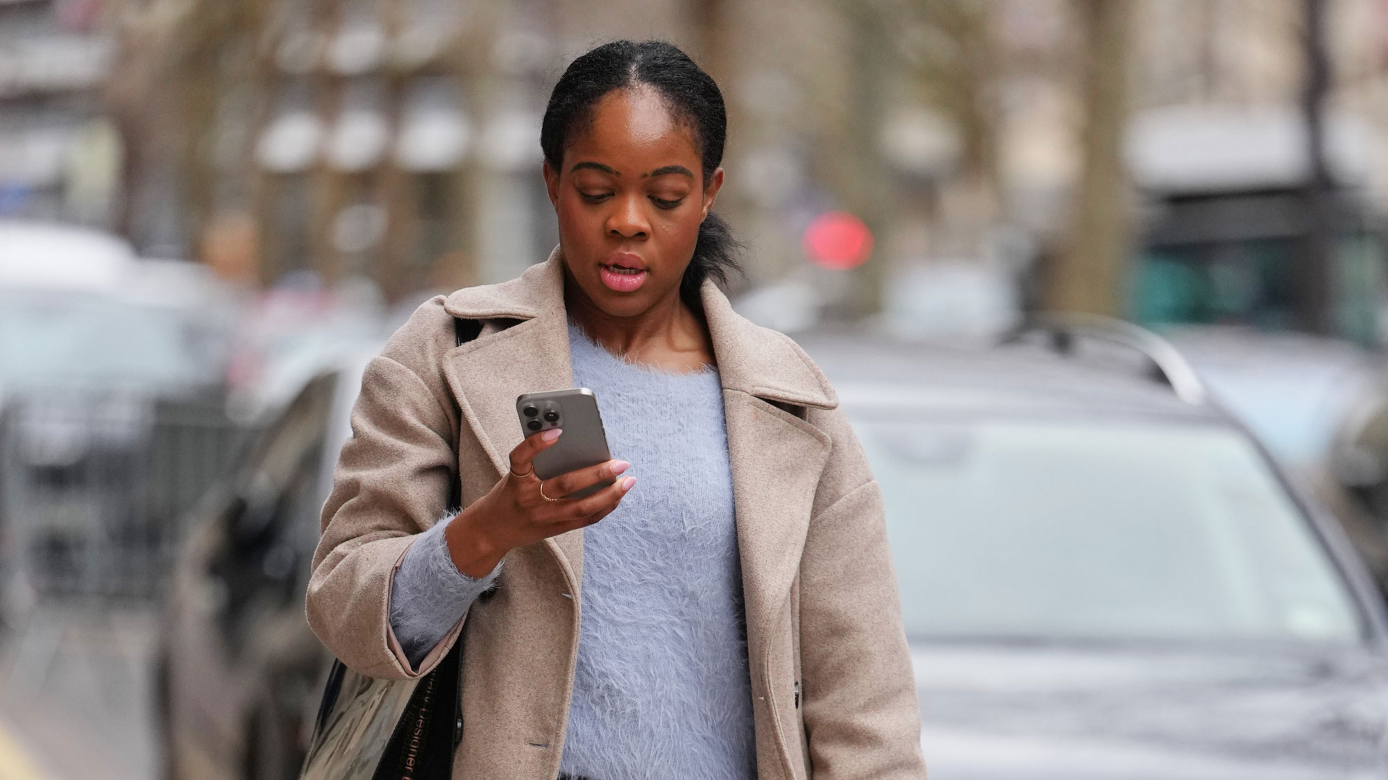 a woman wears a sweater and a trench coat