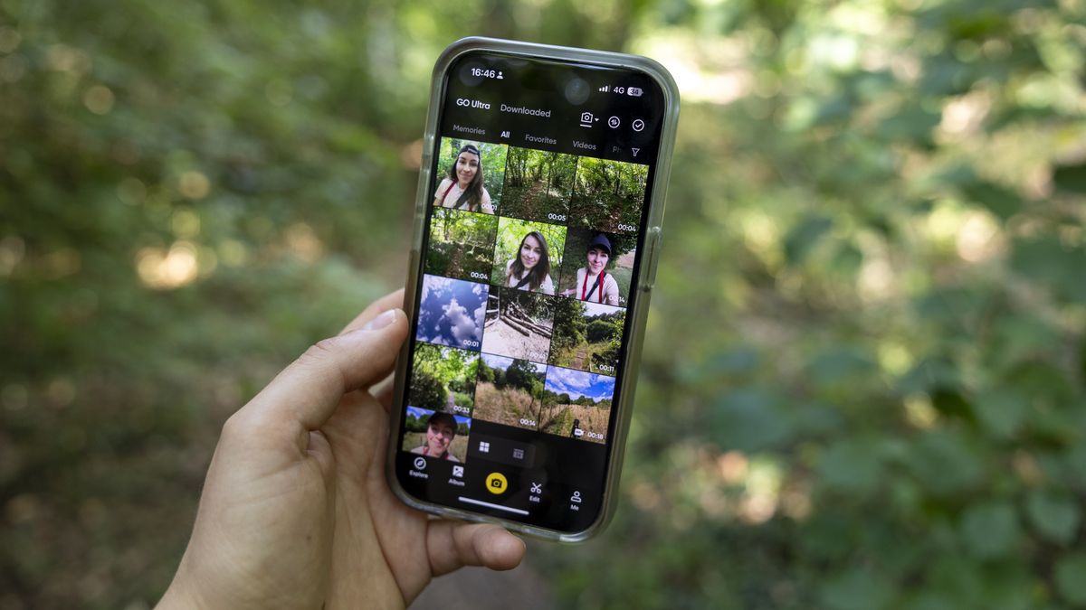 The Insta360 camera app on an iPhone held by a female photographer against a green wooded backdrop
