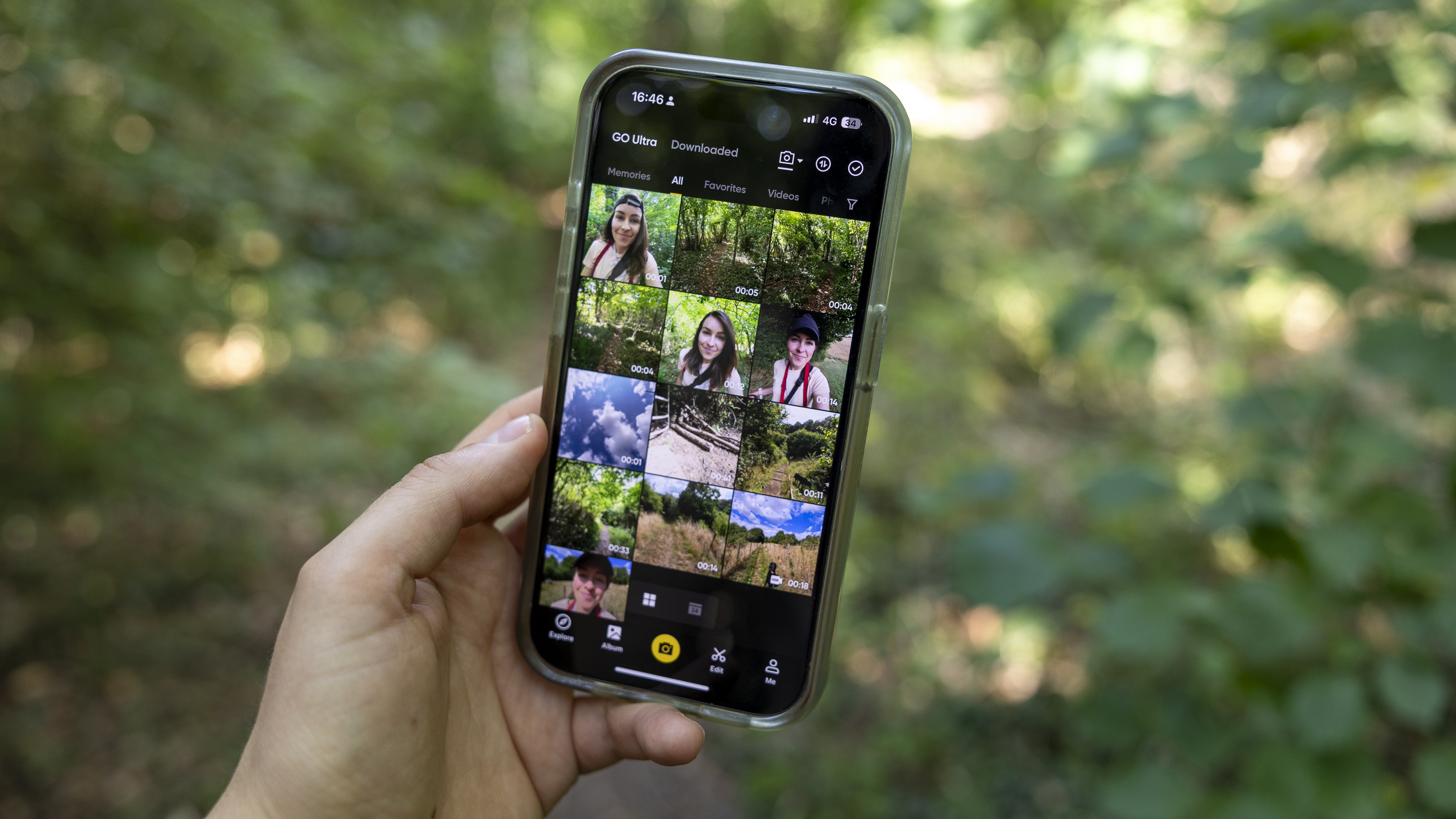 The Insta360 camera app on an iPhone held by a female photographer against a green wooded backdrop