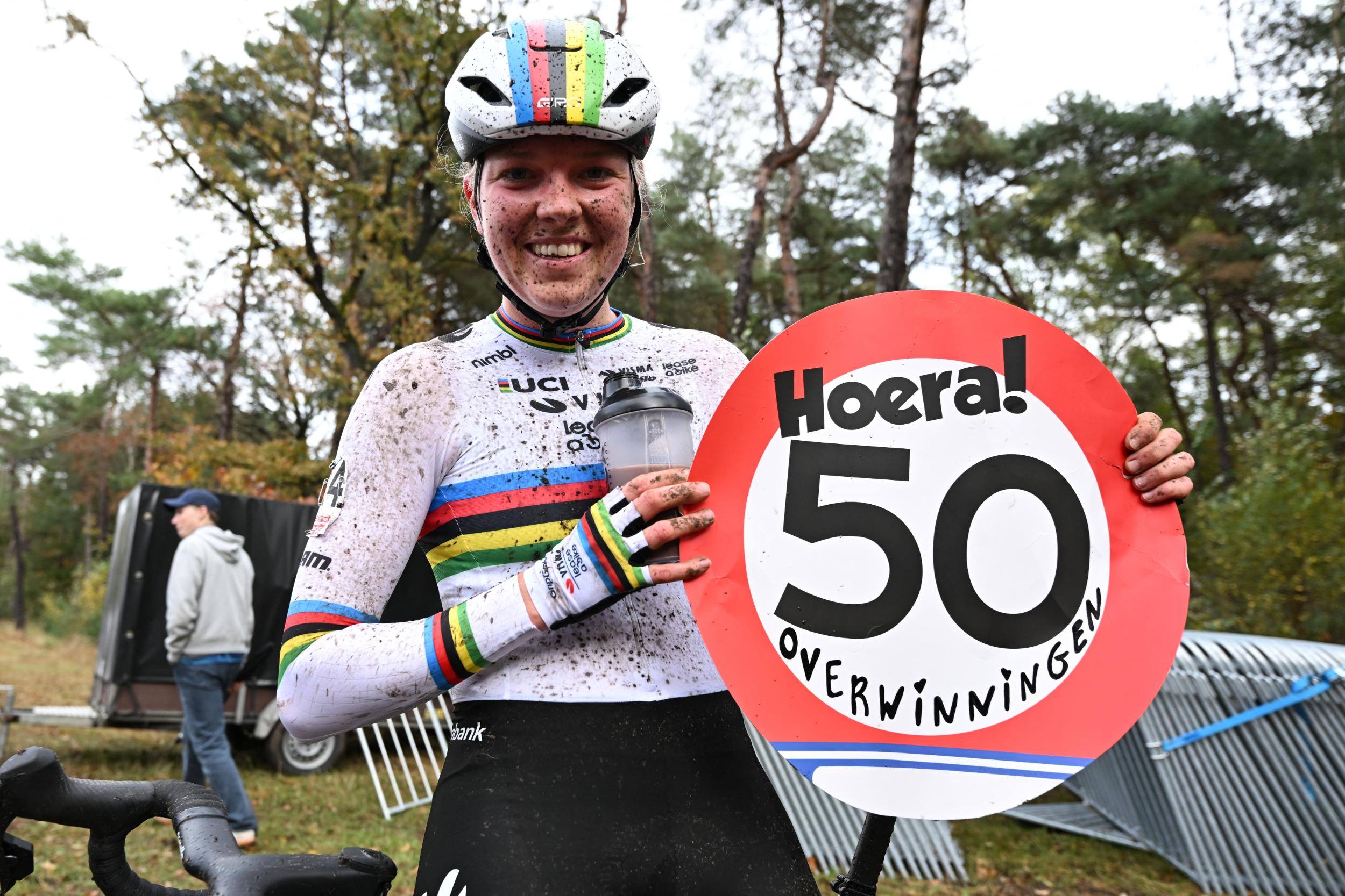 Fem van Empel smiles and holds a sign celebrating her 50th cyclo-cross win