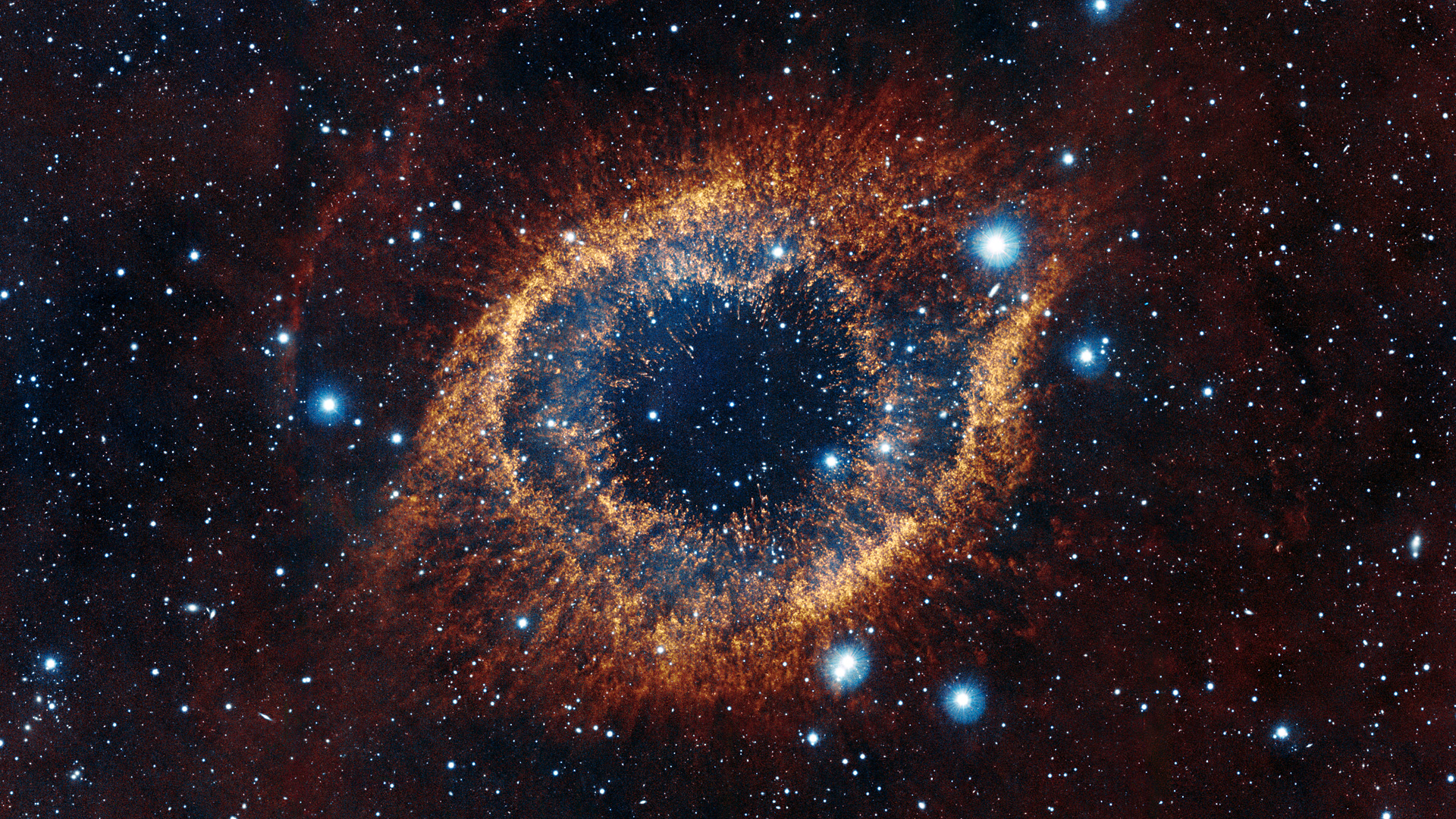 Helix nebula looks like an eye staring back at you, with a dark center and brown outline against a backdrop of stars.