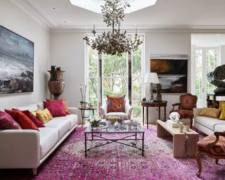 A chandelier in a grand scheme with red oriental rug demonstrating small living room lighting ideas.