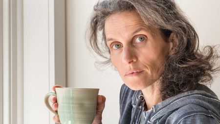 A quizzical-looking woman takes a sip of coffee.