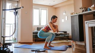 Woman using body weight to workout at home with yoga mat