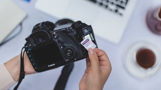 Samsung memory card being inserted into a DSLR camera: best memory cards for cameras