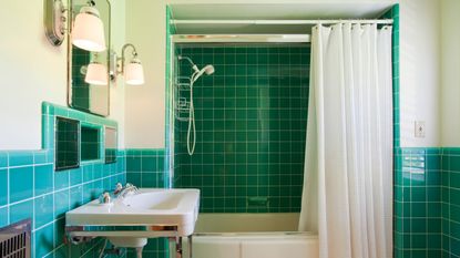 Green tiled bathroom with white suite and shower curtain