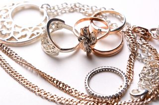 A variety of pre-loved silver and rose gold jewellery on a white background.