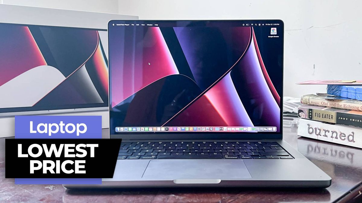 MacBook Pro 14 laptop on a wooden desk next to a pile of books