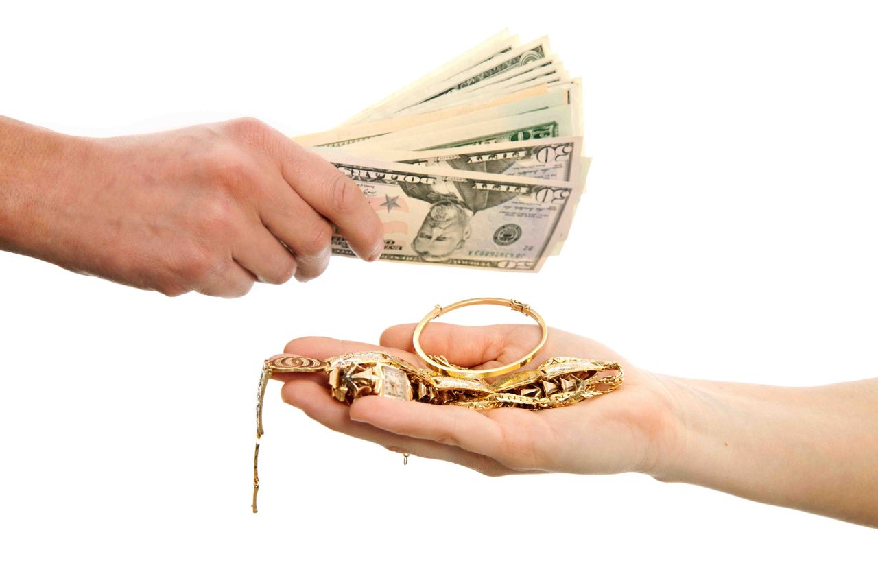 photo of hand with money and hand with gold jewelry