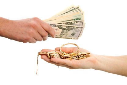photo of a hand with money and a hand with gold jewelry