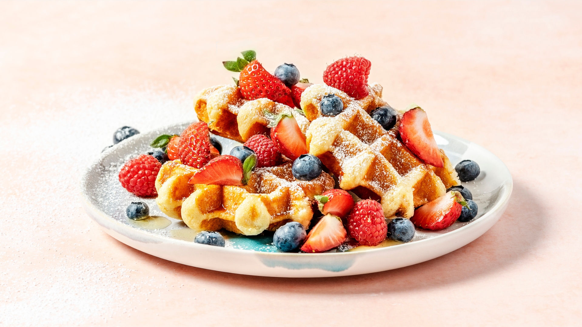 A white plate filled with Belgian waffles and fruit