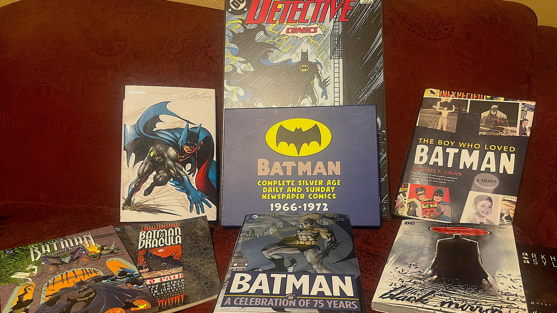 Batman comic books and graphic novels on a red couch