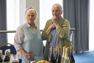 Margaret (Annette Badland) and Brenda (Gemma Jones) stand in the function room at the rugby club. Margaret has her hand on Brenda's shoulder, and Brenda has her left hand over her mouth in alarm