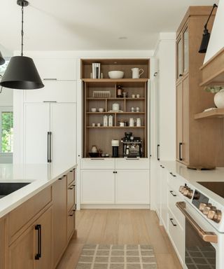 A white and wood kitchen with a designated coffee station in one of the full length cabinets