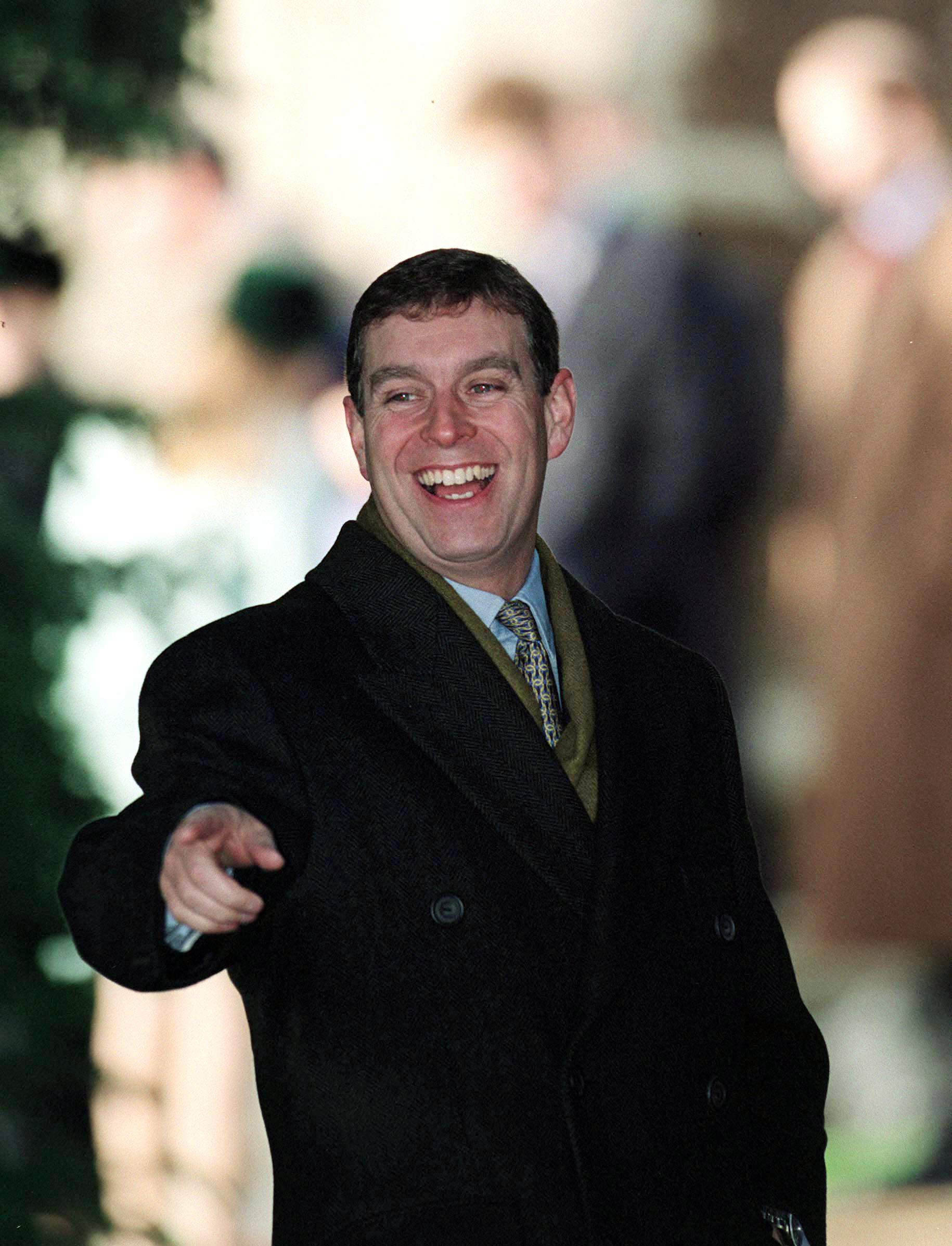 Prince Andrew wearing a coat and tie and laughing on Christmas Day 1999