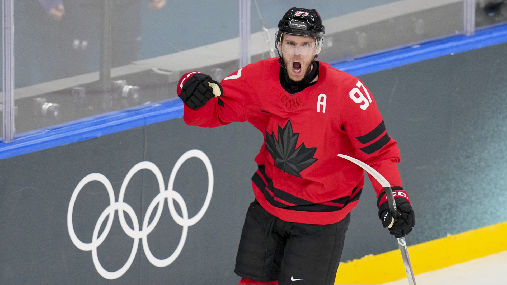 Connor McDavid of Canada celebrates in front of the Olympic Rings after scoring a goal during a 2026 Winter Olympics Ice Hockey match in Milan, Italy.
