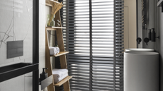 A bathroom with a rack, a modern vanity sink, and marble tiles, with venetian blinds