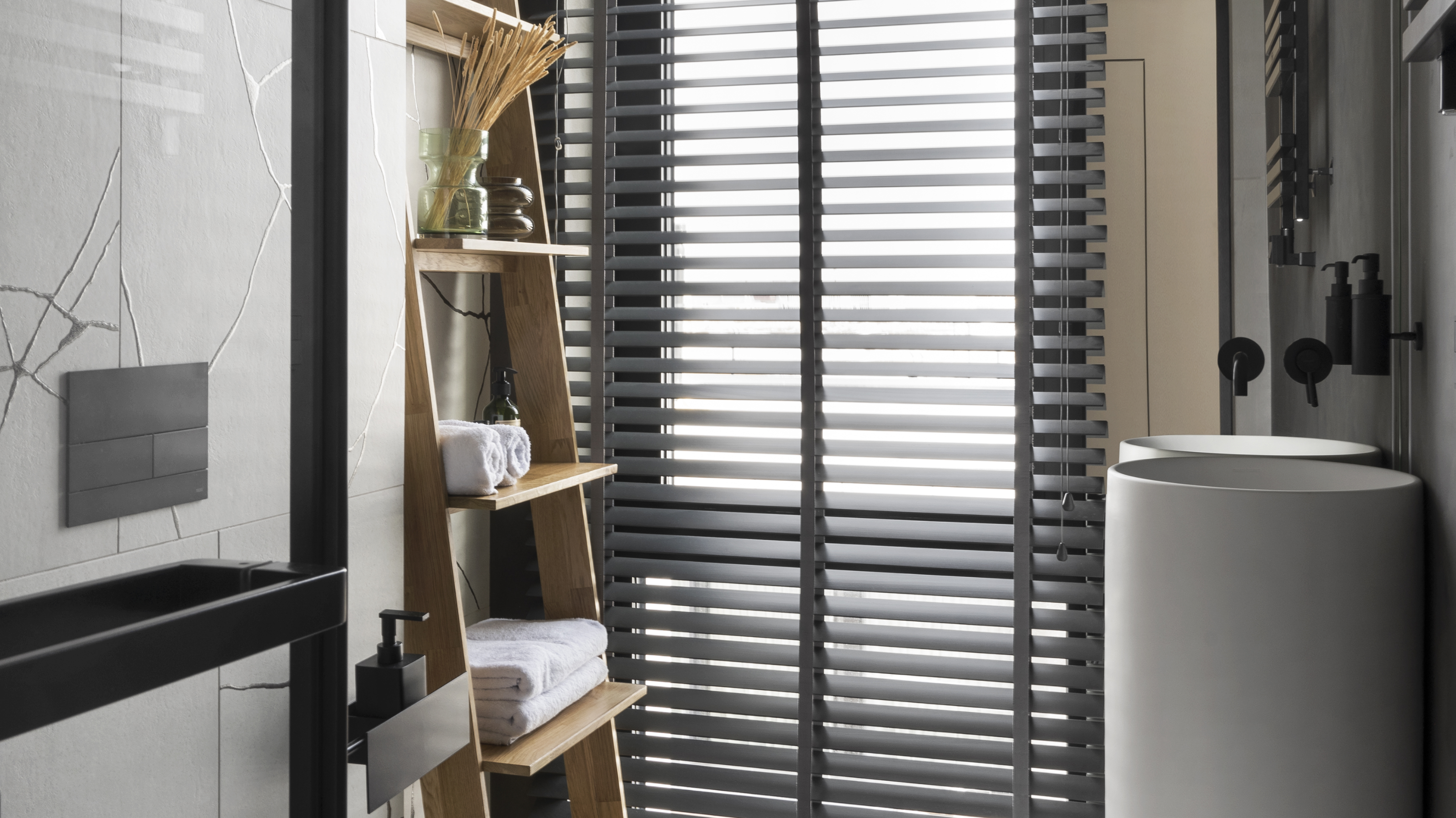 A bathroom with a rack, a modern vanity sink, and marble tiles, with venetian blinds