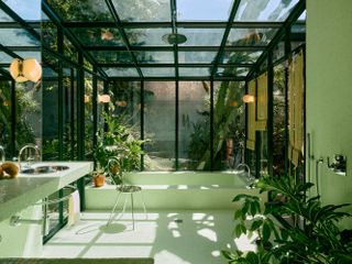 A bathroom designed with green floor and wall tiles, with glass ceiling and windows