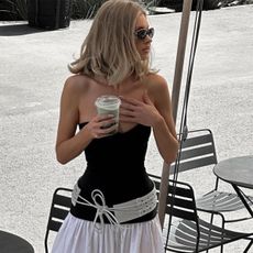 Elsa Hosk wearing a black-and-white drop-waist Helsa dress with a large belt at a coffee shop. 