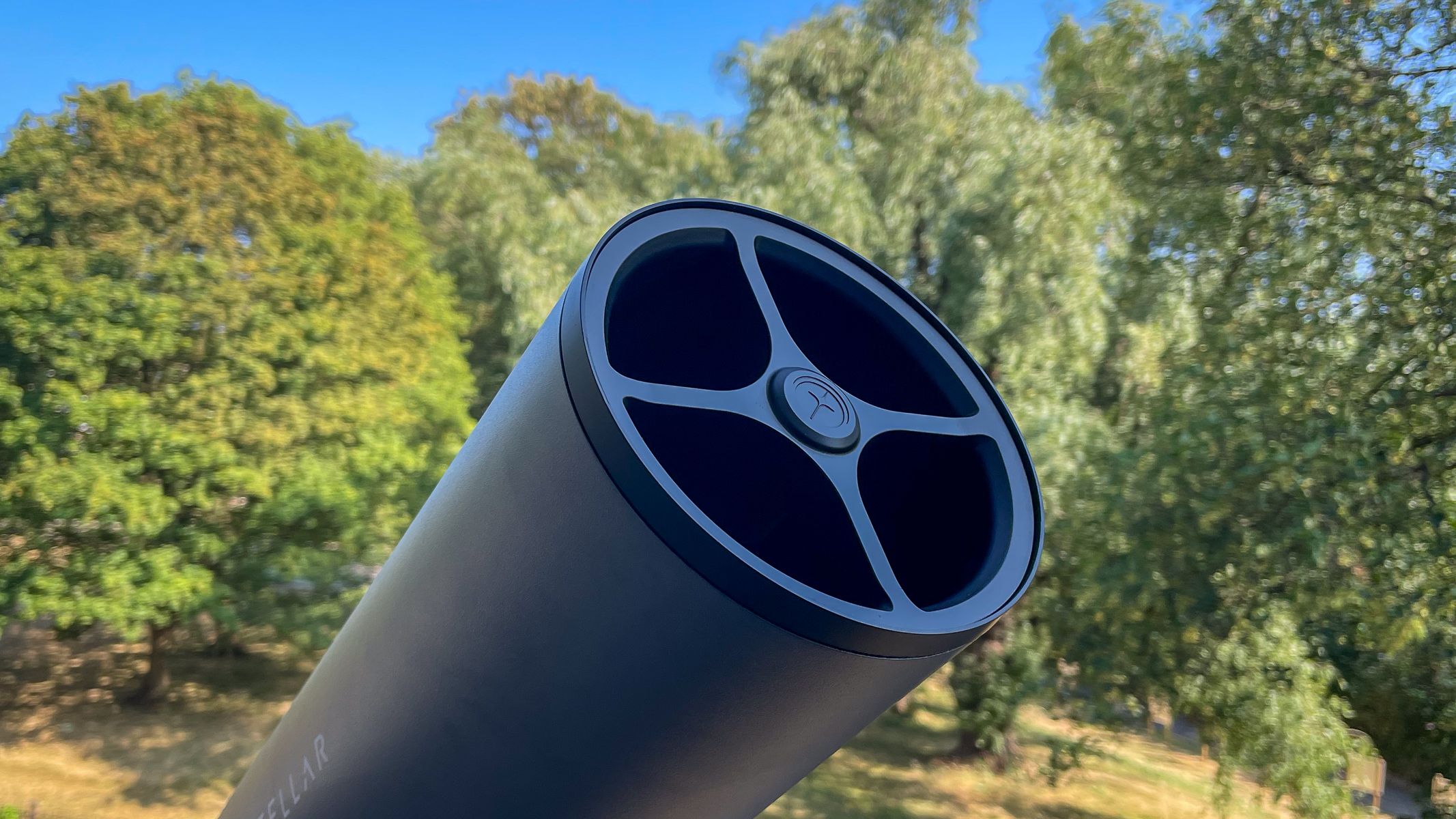 The Unistellar eVscope 2 without solar filter attached with trees in the background.