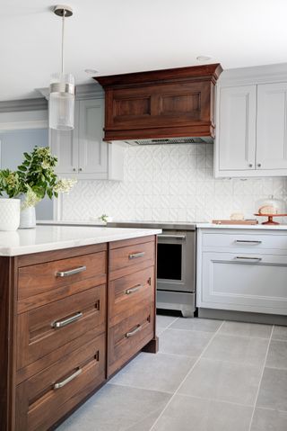 kitchen with some white units, white textured backsplash tiles, pale gray floor tiles, some wooden cabinetry, wooden cooker hood,