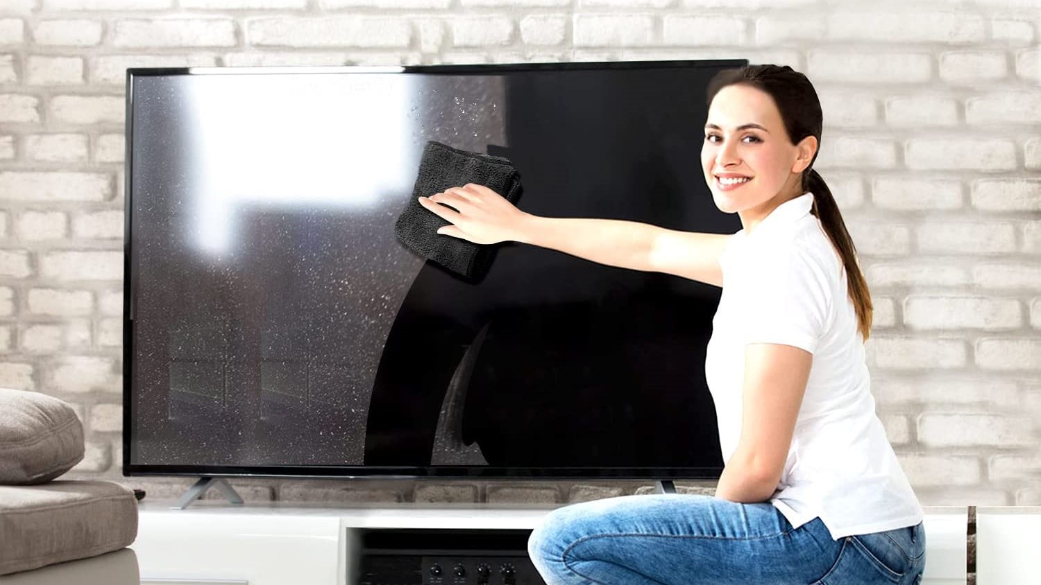 A woman cleaning a TV with Screen Cleaner Spray.