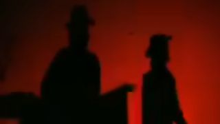The Edge and Bono of U2 in silhouette in front of a red background