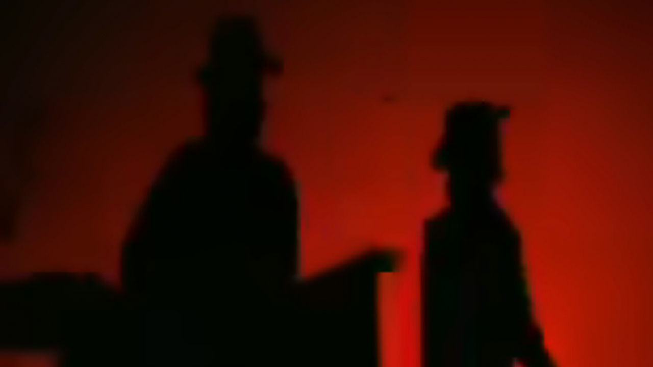 The Edge and Bono of U2 in silhouette in front of a red background