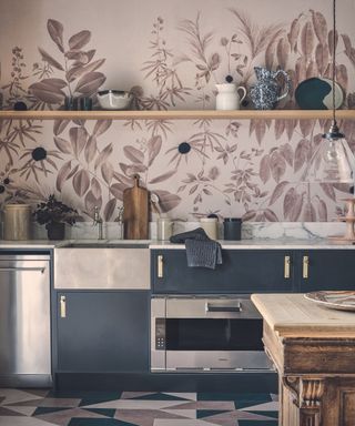 Kitchen with metal and dark blue cupboards, marbled worktop, pink and white floral wall and tiled floor.