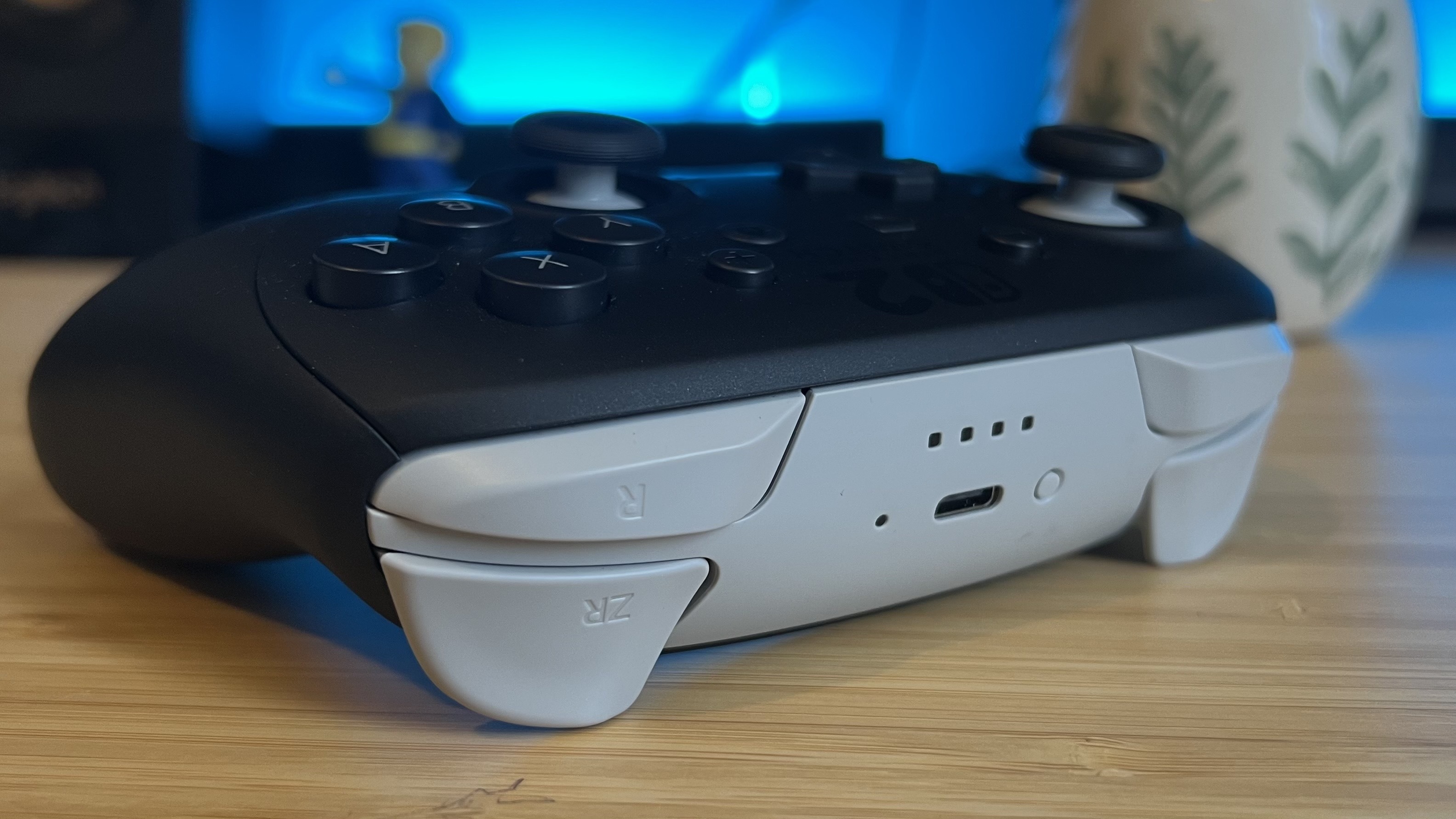 Front edge of Nintendo Switch 2 Pro Controller showing gray color on a wooden desk