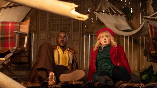 The Doctor (Ncuti Gatwa) and Joy (Nicola Coughlan) sitting on the floor of a cabin-like room, looking up at something that concerns them.