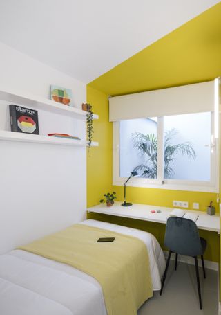 A bedroom with a yellow-painted work corner