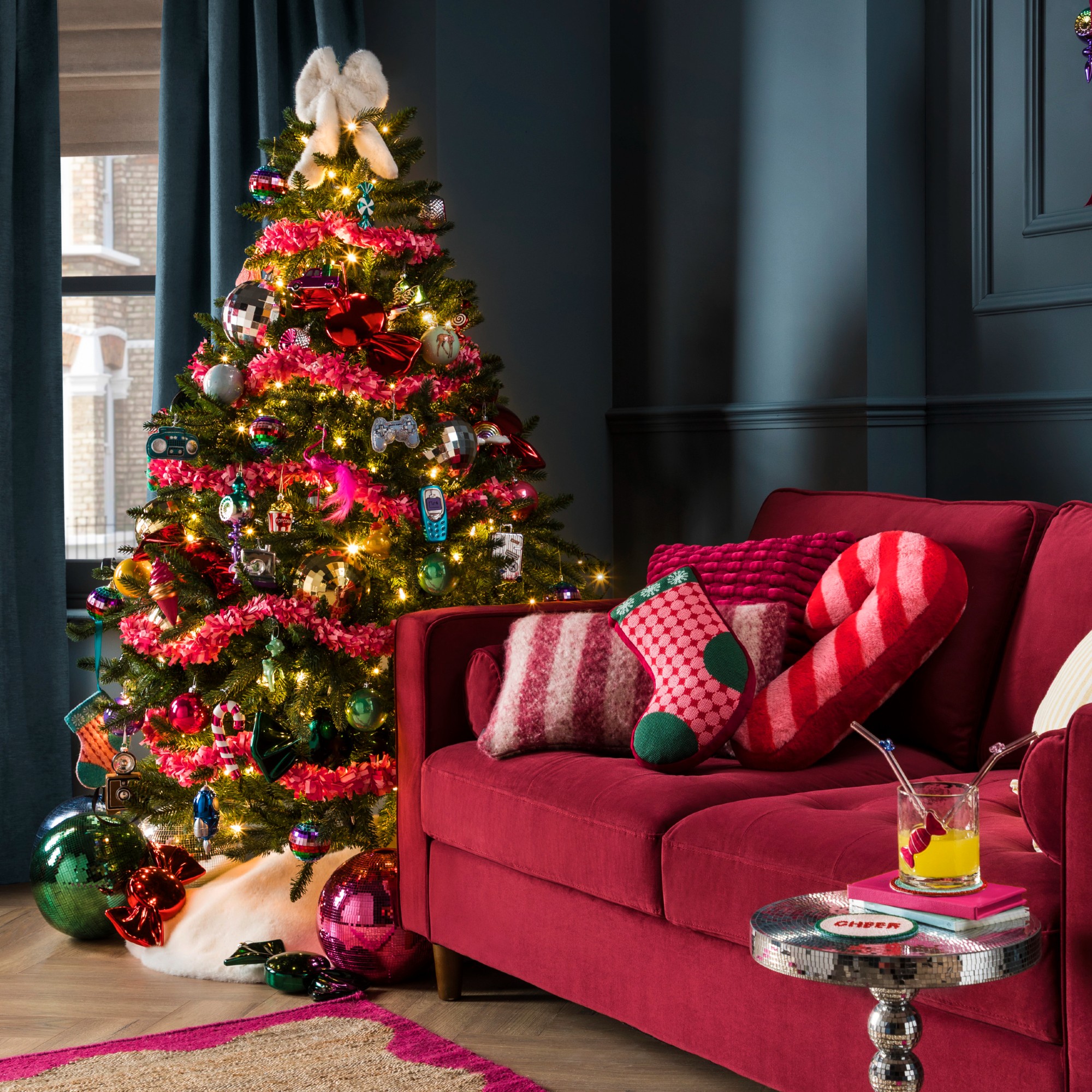 A living room with a Christmas tree decorated with Christmas decorations from Dunelm, including a white faux fur bow tree topper