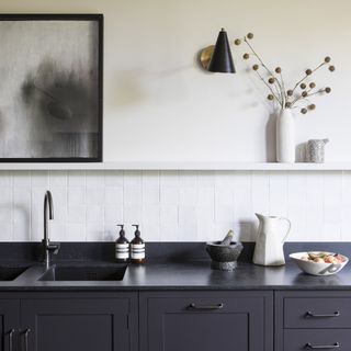 Kitchen with black worktop and sink with white open shelving