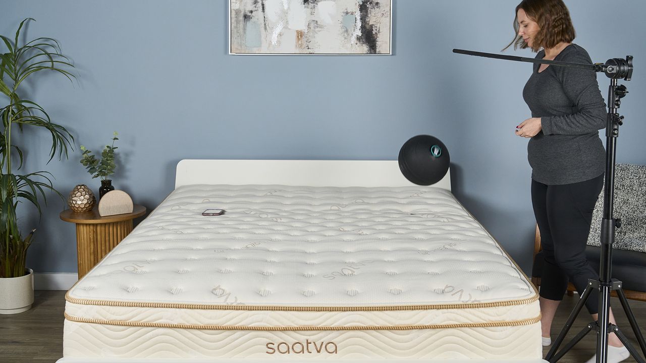 Image shows the 5kg slam ball being released onto the Saatva Classic mattress. A device with a robust accelerometer app sits in a standardized spot on the opposite side of the mattress where it's measuring the motion dampening speed of the Saatva Classic. The Saatva performed very well in this test, absorbing a high amount of motion from the initial impact and deadening the resulting motion very quickly.