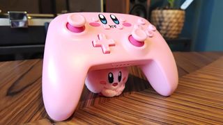 PowerA Kirby controller being held up by Kirby plush