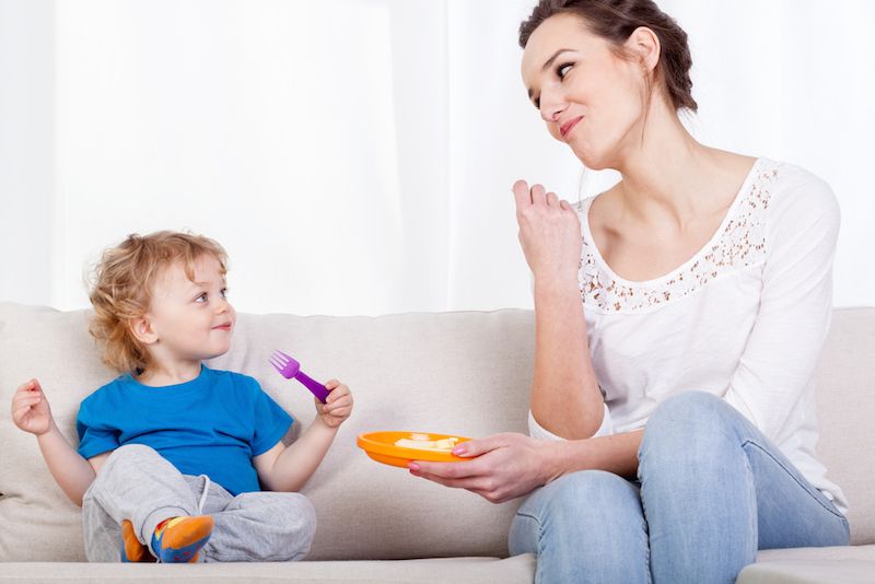 A mom and toddler eat a snack together