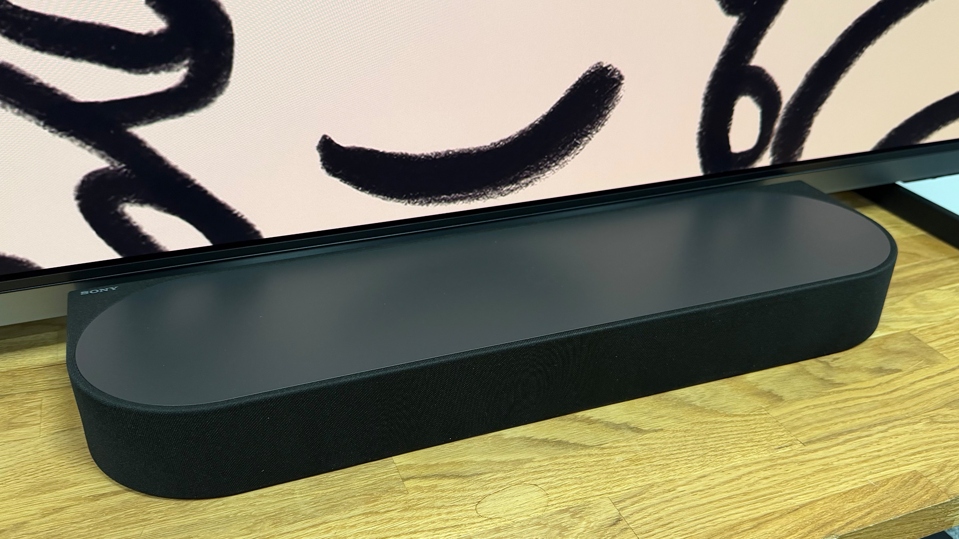 Sony Bravia Theatre Trio + Rear 9 and Sub 9 surround sound system soundbar unit on wooden AV rack in front of black and white painti